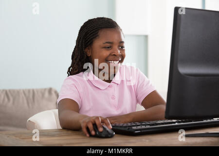 Portrait Of An African Smiling Girl Using Computer At Home Stock Photo