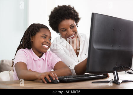 An African Mother And Daughter Looking At Computer On Table At Home Stock Photo
