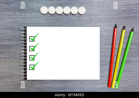 Black notebook with three pencils lie on the table. Notepad with pencils. Stock Photo