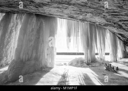 A sun burst shines around an ice column curtain on Grand Island near Munising Michigan in winter Stock Photo