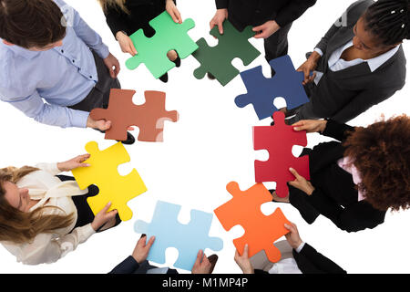 High Angle View Of Businesspeople Solving Jigsaw Puzzle Stock Photo