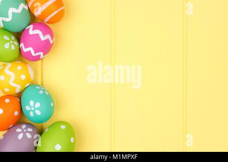Colorful Easter egg side border against a yellow wood background Stock Photo