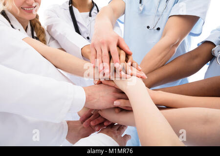 Group Of Happy Doctors Stacking Their Hands Against White Background Stock Photo