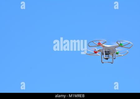 View on flying quadrocopter in clear blue sky in sunlight.Isolated. Stock Photo