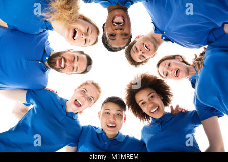 Group Of Smiling Janitors Forming Huddle Against White Background Stock Photo
