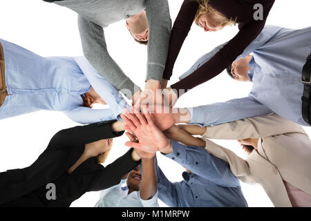 Low Angle View Of College Students Stacking Their Hands Against White Background Stock Photo