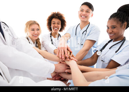 Group Of Happy Doctors Stacking Their Hands Against White Background Stock Photo