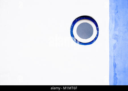 White stone wall with round window and blue accents Stock Photo