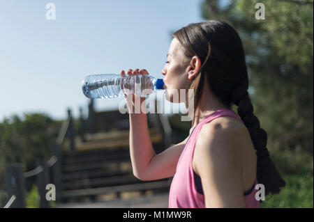 woman drinking water from a bottle after exercise. Outdoors. Stock Photo