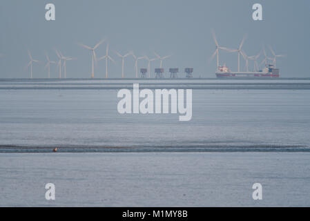 Kentish Flats Offshore Wind Farm and Red Sands Maunsell Forts in the mouth of the Thames Estuary off the Essex and Kent coasts. Cargo ship passing by Stock Photo