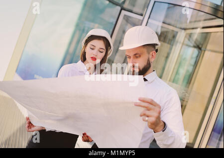 A man with a beard and a woman in business clothes is studying drawings and documents for a new project Stock Photo