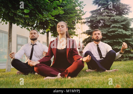 Three friends in business clothes barefoot doing yoga  Stock Photo