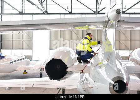 ground staff at the airport checks the technology and safety of a jet in the hangar Stock Photo