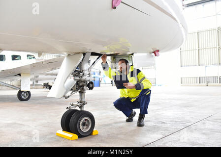 Ground personnel at the airport check the hydraulic system of the landing gear of the aircraft Stock Photo
