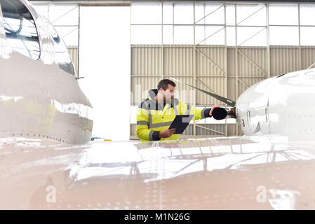 Aircraft mechanic inspects and checks the technology of a jet in a hangar at the airport Stock Photo