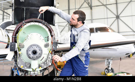 Aircraft mechanic repairs an aircraft engine in an airport hangar Stock Photo