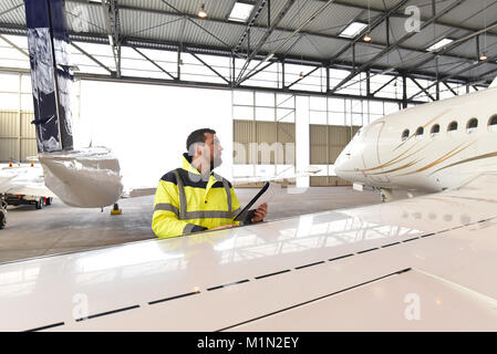 Aircraft mechanic inspects and checks the technology of a jet in a hangar at the airport Stock Photo