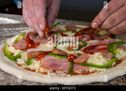 Putting ingredients on pizza Stock Photo