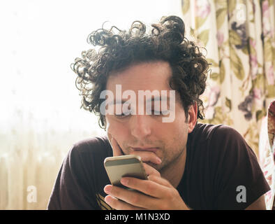 Portrait of a relaxed Caucasian man using a smart phone at home Stock Photo