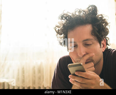 Portrait of a relaxed Caucasian man using a smart phone at home Stock Photo