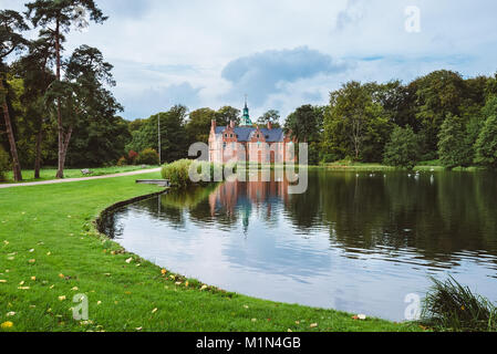 Bath House hunting lodge reflected on the lake water near Frederiksborg castle in Copenhagen, Denmark. Romantic park around lonely pond with water bir Stock Photo