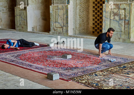 Isfahan, Iran - April 24, 2017: a Muslim is squatting in Jame  mosque, an Iranian man is sleeping nearby. Stock Photo