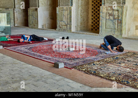 Isfahan, Iran - April 24, 2017: Muslim is sitting on a carpet in Jame  mosque and praying, men sleep on the carpet. Stock Photo