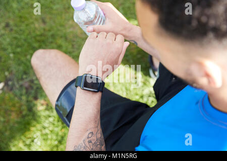 Young male athlete checking smartwatch, over shoulder view Stock Photo