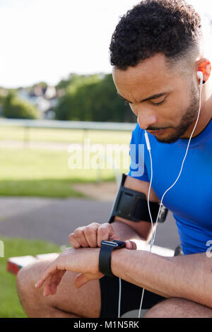 Young male athlete using fitness app on smartwatch, side view Stock Photo