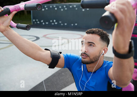 Young male athlete using outdoor gym in park, close up Stock Photo