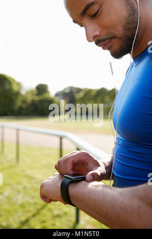 Male athlete at running track setting smartwatch app Stock Photo