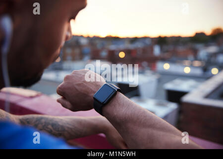 Male urban runner checks fitness app on smartwatch, close up Stock Photo