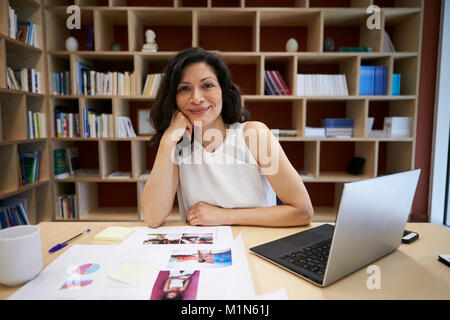 Middle aged female creative using laptop smiling to camera Stock Photo