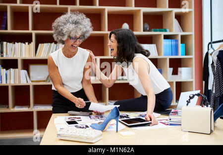 Two happy women talking in a creative media office, close up Stock Photo