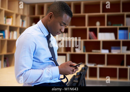 Young black man using smartphone in a boardroom, close up Stock Photo