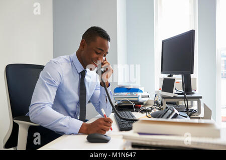 Young black businessman using the phone at his office desk Stock Photo