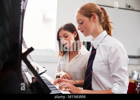 Female Pupil With Teacher Playing Piano In Music Lesson Stock Photo