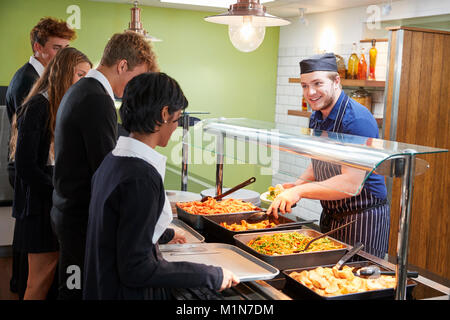 Teenage Students Being Served Meal In School Canteen Stock Photo