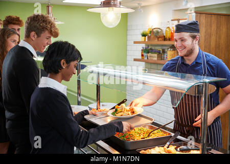 Teenage Students Being Served Meal In School Canteen Stock Photo