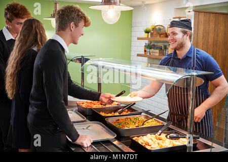 Teenage Students Being Served Meal In School Canteen Stock Photo