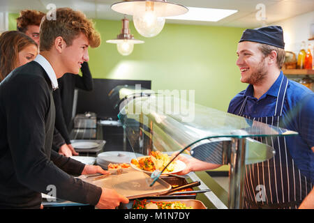 Teenage Students Being Served Meal In School Canteen Stock Photo