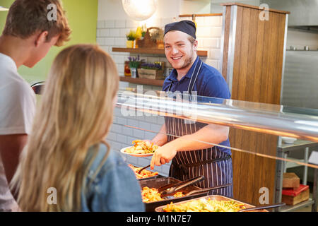 Teenage Students Being Served Meal In School Canteen Stock Photo