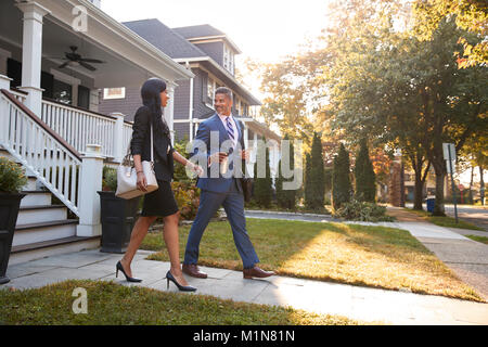 Business Couple Leaving Suburban House For Commute To Work Stock Photo