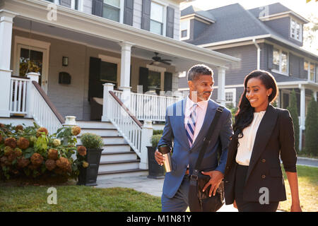 Business Couple Leaving Suburban House For Commute To Work Stock Photo