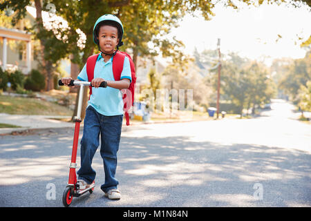 Young Boy Riding Scooter Along Street To School Stock Photo