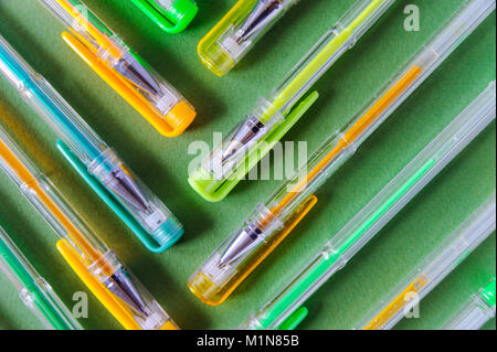 Ballpoint pens of different colors on a green background. Stock Photo