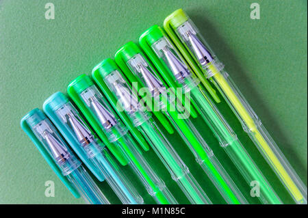 Ballpoint pens of different colors on a green background. Stock Photo