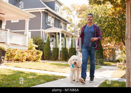 Man Walking Dog Along Suburban Street Stock Photo