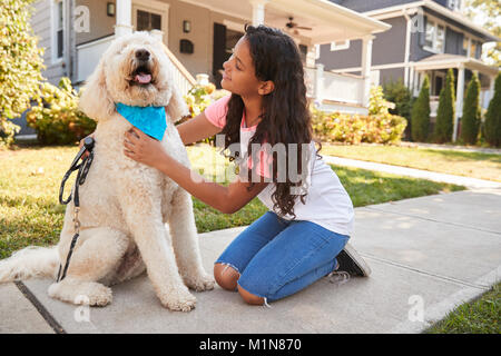 Girl Walking Dog Along Suburban Street Stock Photo