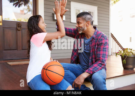 Father And Daughter Discussing Basketball On Porch Of Home Stock Photo
